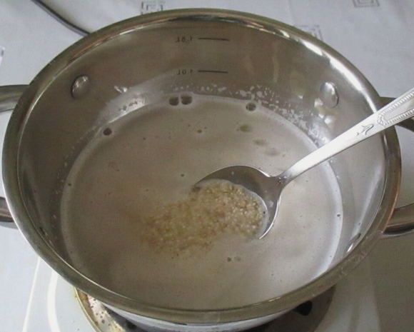 Ячневая каша на молоке в кастрюле на плите