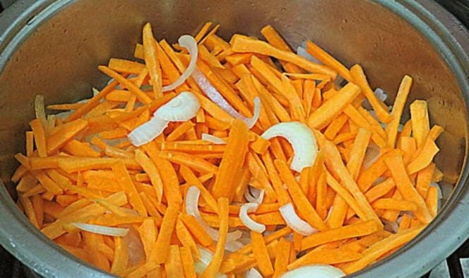 Рассыпчатый плов с рисом, курицей и морковью в кастрюле на плите