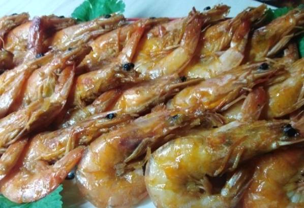 Замороженные неочищенные креветки с чесноком и соевым соусом на сковороде