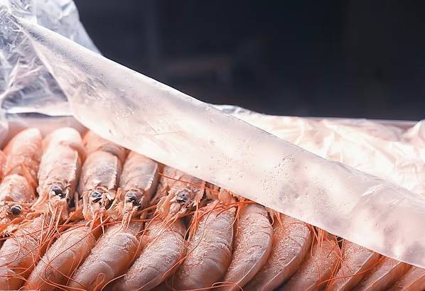 Замороженные неочищенные креветки с чесноком и соевым соусом на сковороде