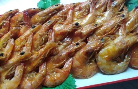 Замороженные неочищенные креветки с чесноком и соевым соусом на сковороде