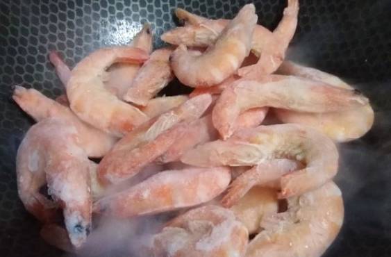 Замороженные неочищенные креветки с чесноком и соевым соусом на сковороде