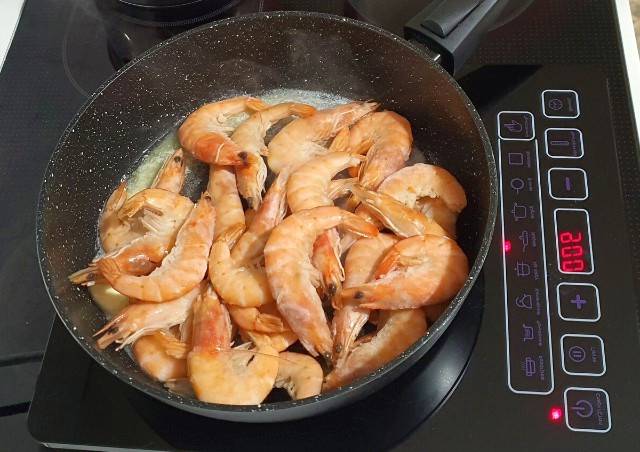 Замороженные неочищенные креветки с чесноком на сковороде